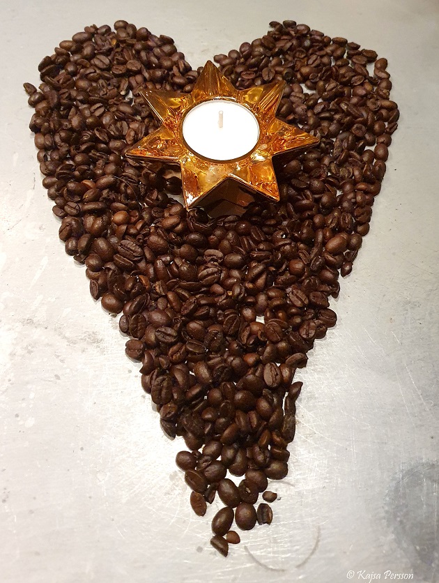 Kaffe bönor som bildar ett hjärta med ett guldrigt stjärnljus
