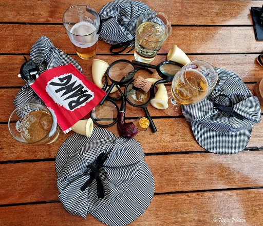 Detektivhattar, förstoringsglas, öl, bang, pipor på ett bord